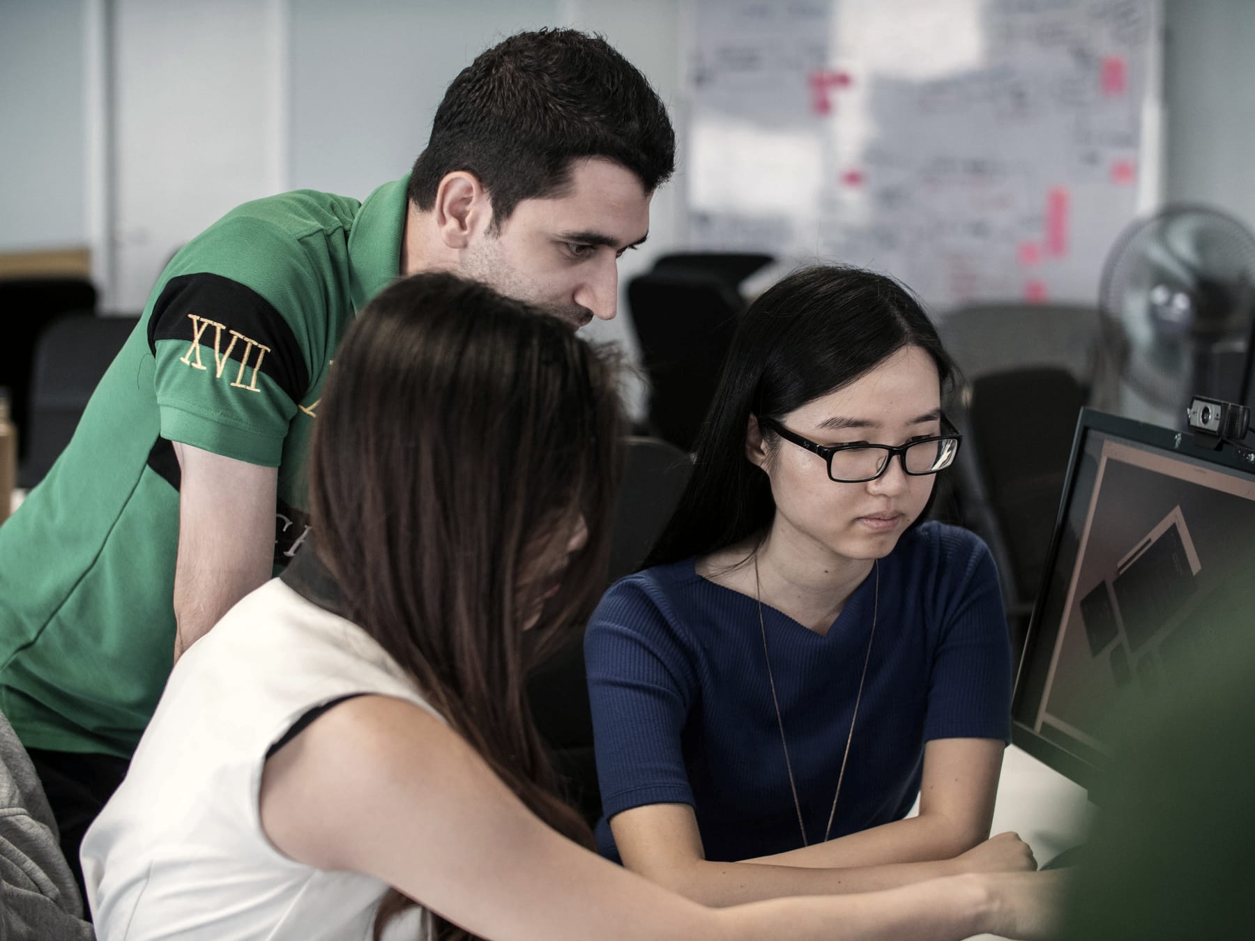 A colleague leans in to review work on a screen